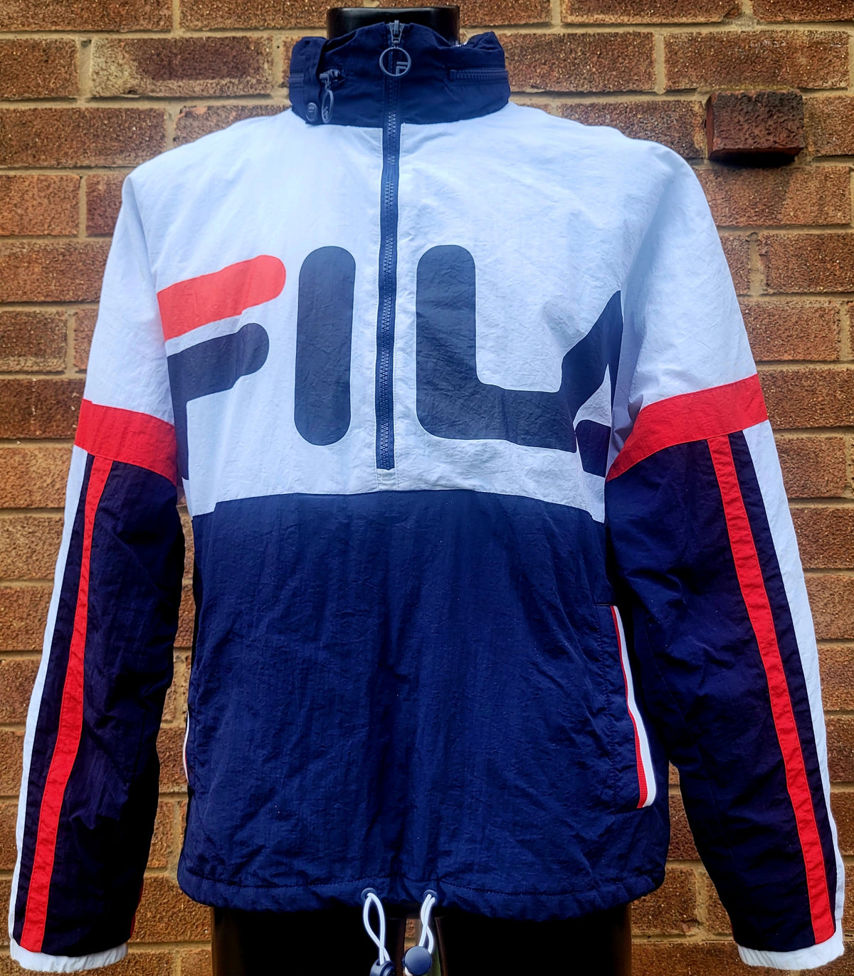 Vintage FILA half zip padded anorak jacket in white, navy and red colour block with oversized FILA logo across the chest, funnel neck, insulated lining and adjustable drawcord hem.